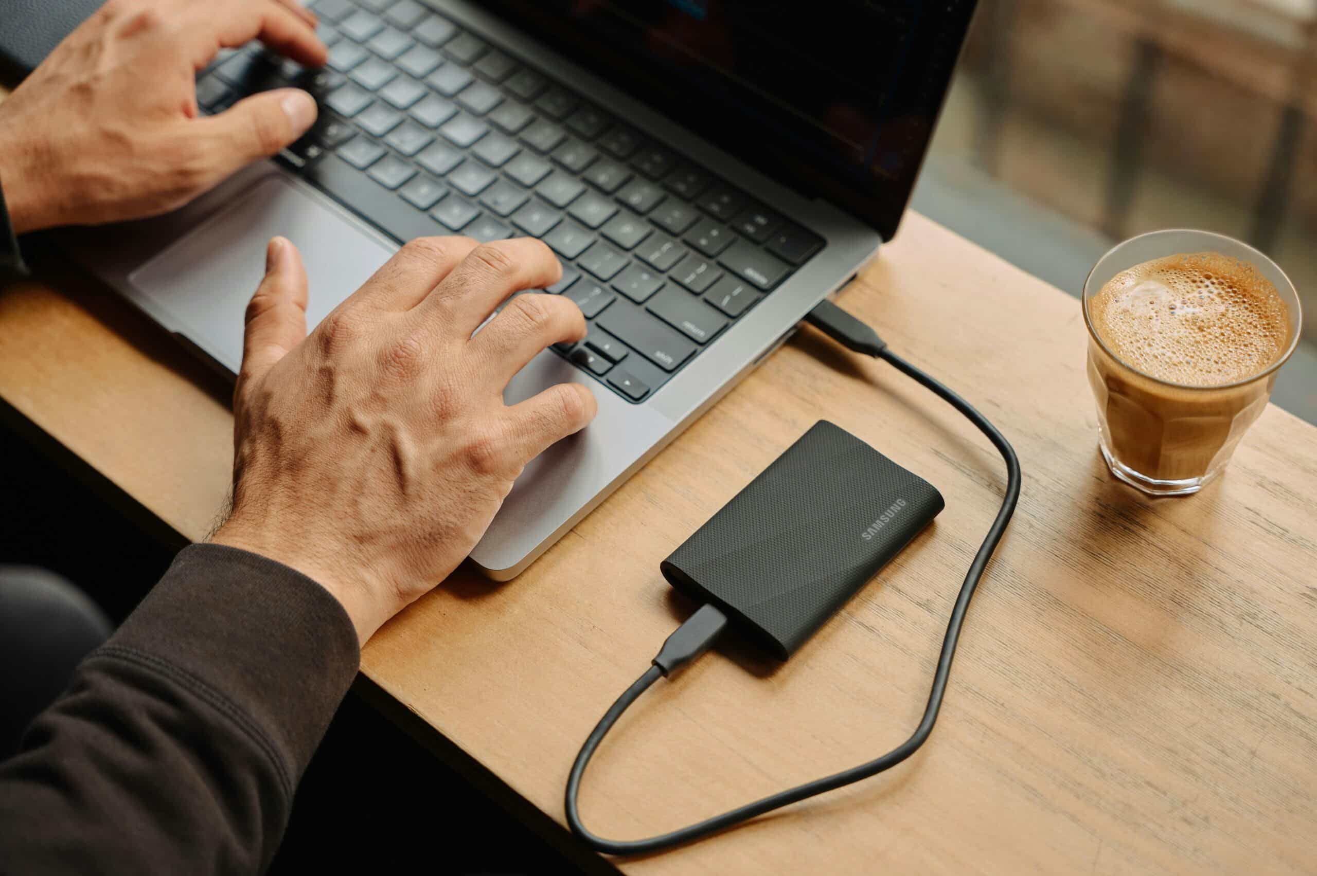 How-Much-Device-Storage-You-Need_-A-Comprehensive-Guide-scaled.jpg A man sitting at a table using a laptop computer